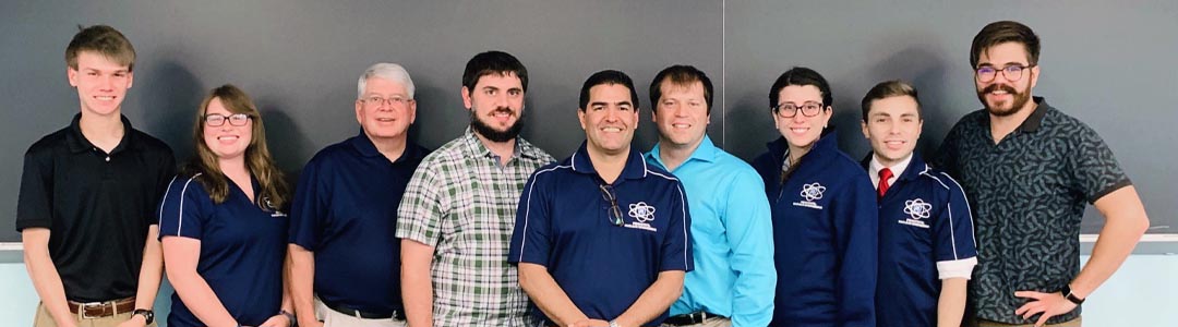 nine people stand in front of a classroom