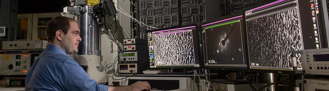 a researcher works at a 3-monitor array in a lab